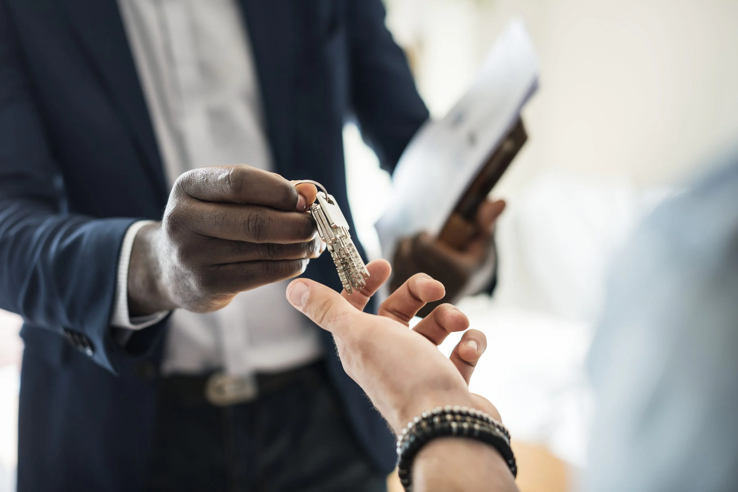 Real estate agent handing the house key to a client Real estate agent handing house keys to a property buyer
